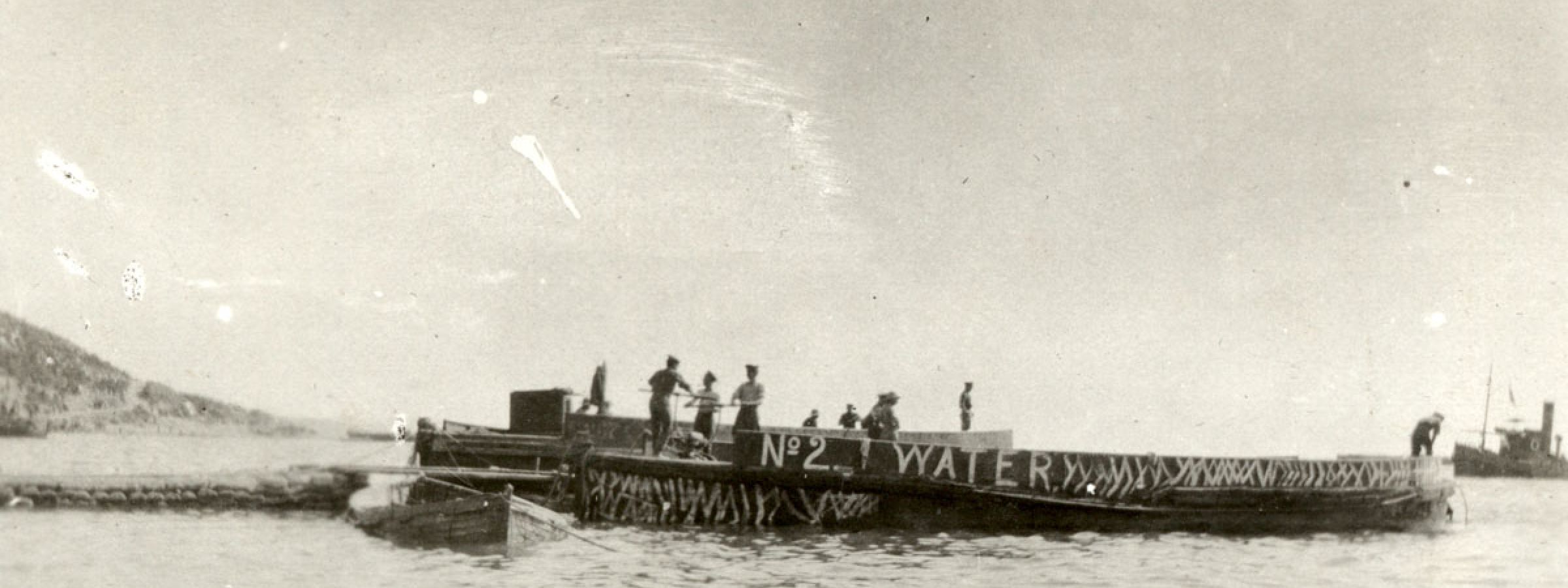 Engineers pump water ashore from a water barge. Ari Burnu is visible in the background.